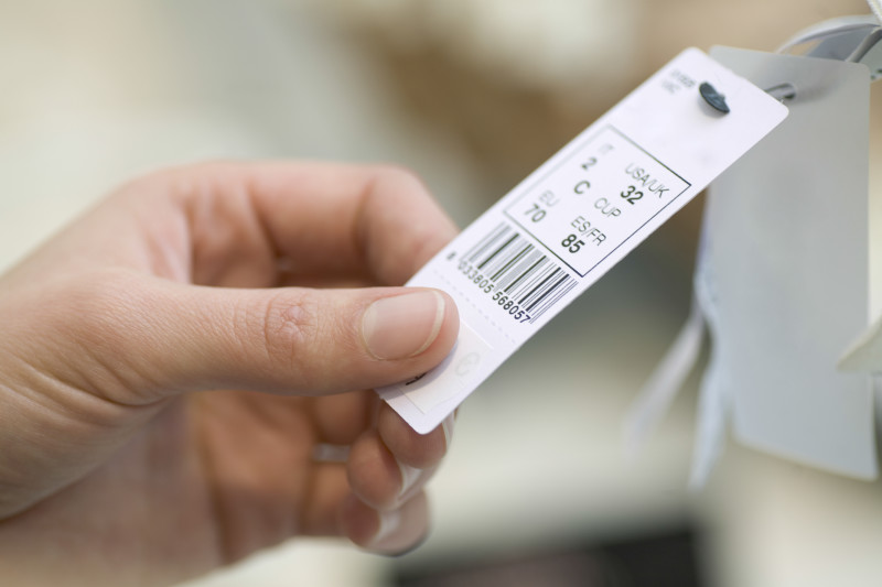 Closeup of woman’s hands holding clothes tag in store